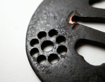 Détail du Kuyō-mon en ko-sukashi sur une tsuba de samouraï ancienne, antiquité japonaise en fer à patine profonde.