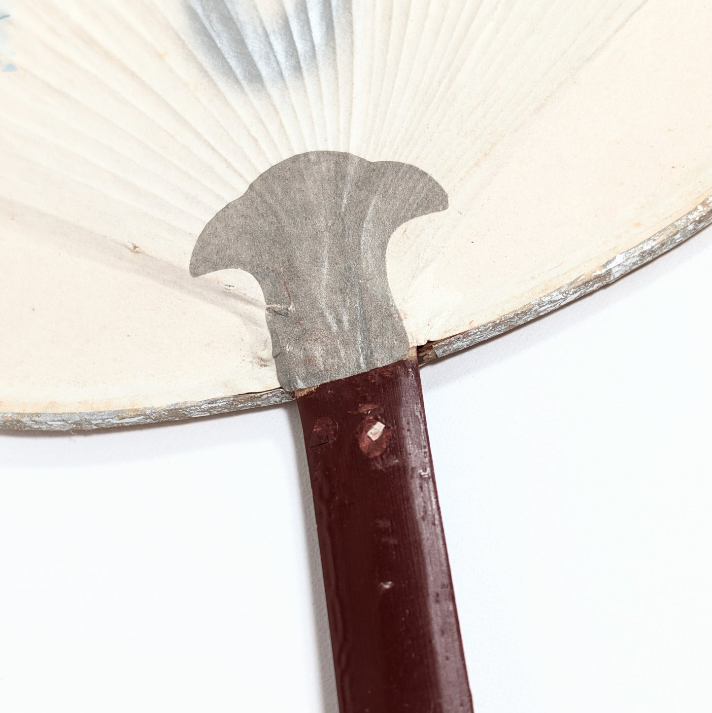 Gros plan du renfort en papier et de la jonction du manche d’un uchiwa japonais vintage.