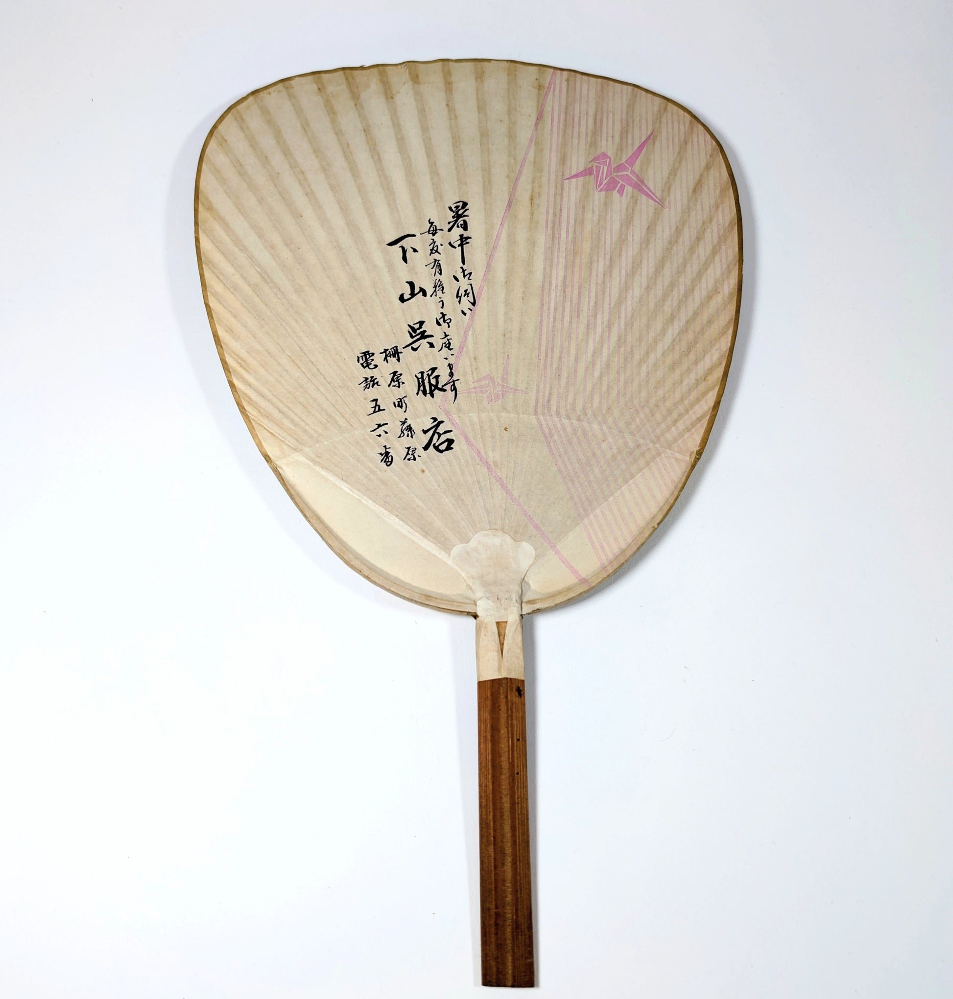 verso d’un éventail japonais uchiwa de l’ère Shōwa avec publicité en calligraphie japonaise et motif de grue
