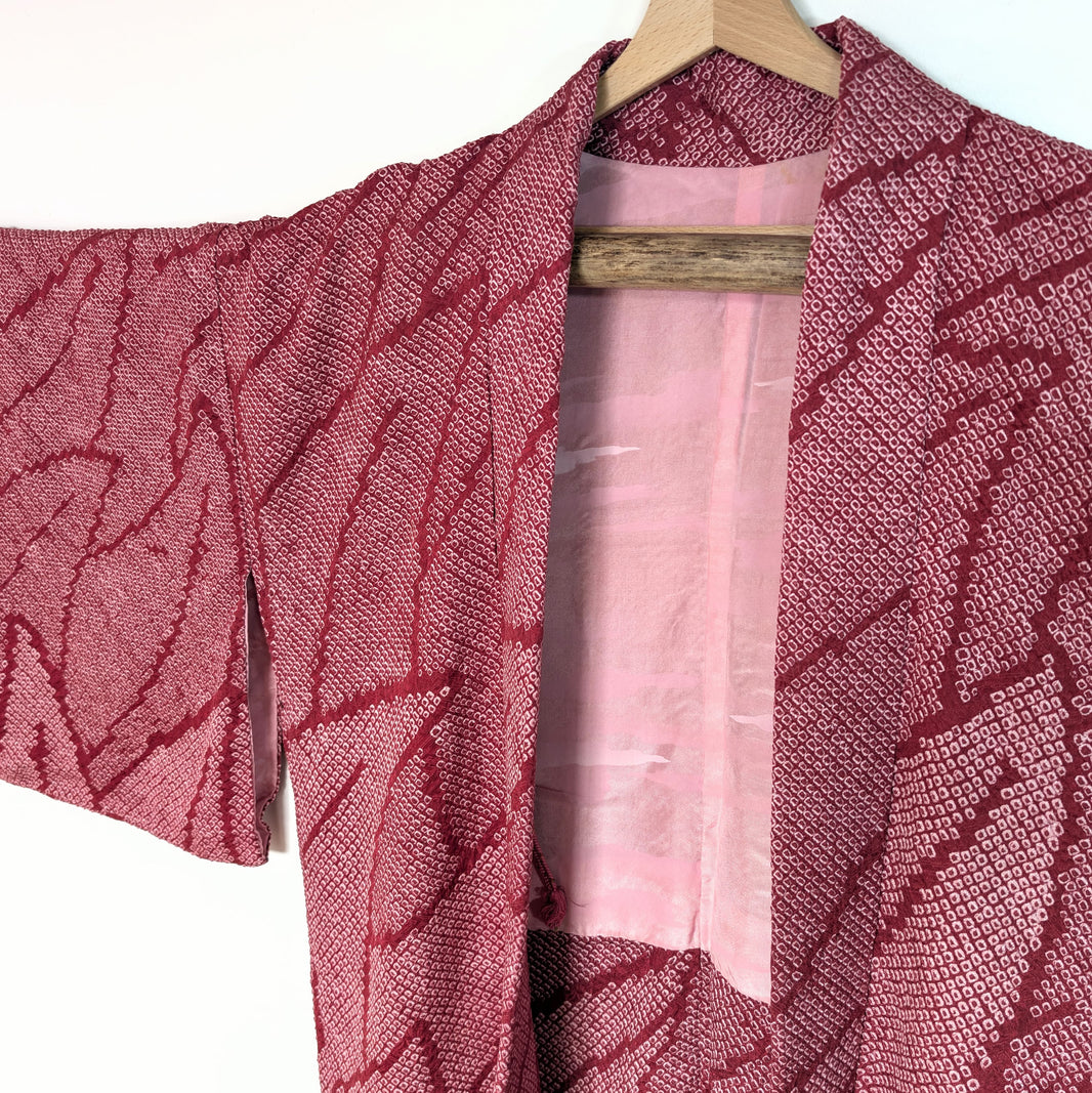 Veste kimono japonaise (haori) en soie shibori, rose intense, motif feuillage stylisé, encolure et doublure visibles.