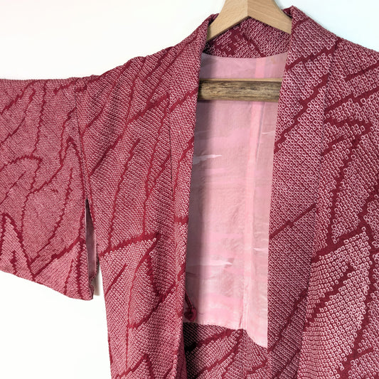Veste kimono japonaise (haori) en soie shibori, rose intense, motif feuillage stylisé, encolure et doublure visibles.