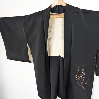 Haori en soie noire habutae, veste japonaise femme avec brillance discrète, doublure ivoire et motif ume sur le pan avant.