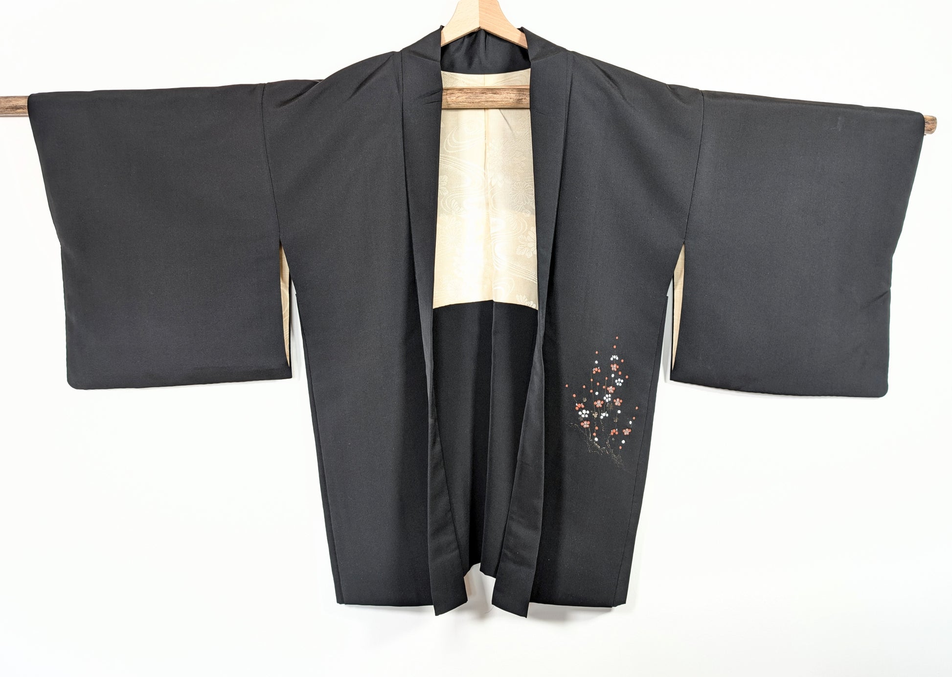 Veste kimono japonaise traditionnelle en soie noire shōken, décor floral ume sur le pan avant et doublure ivoire à motifs japonais.