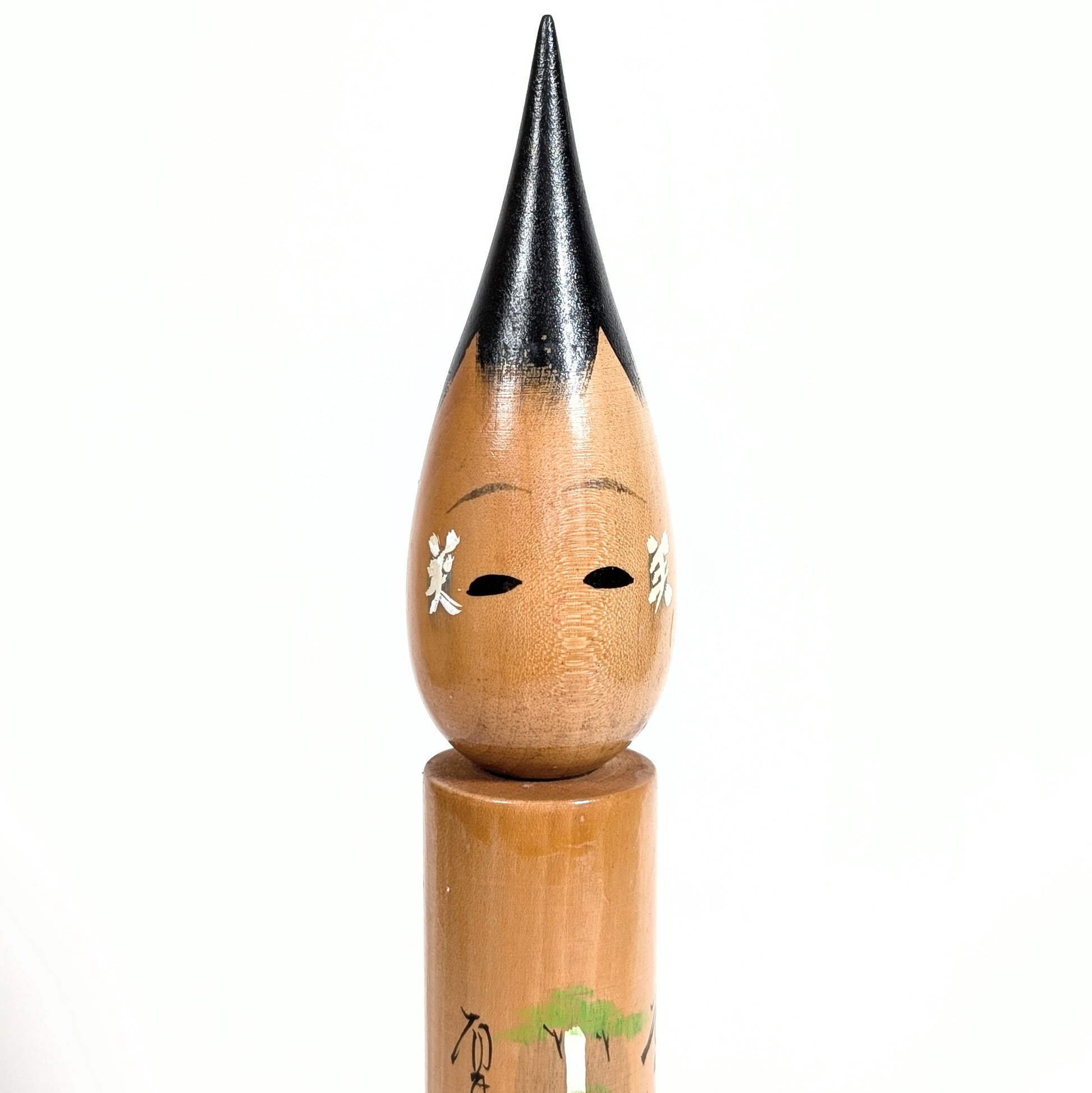 Gros plan du visage d’une fude kokeshi en bois, kanji 美 sur les joues, cheveux noirs laqués
