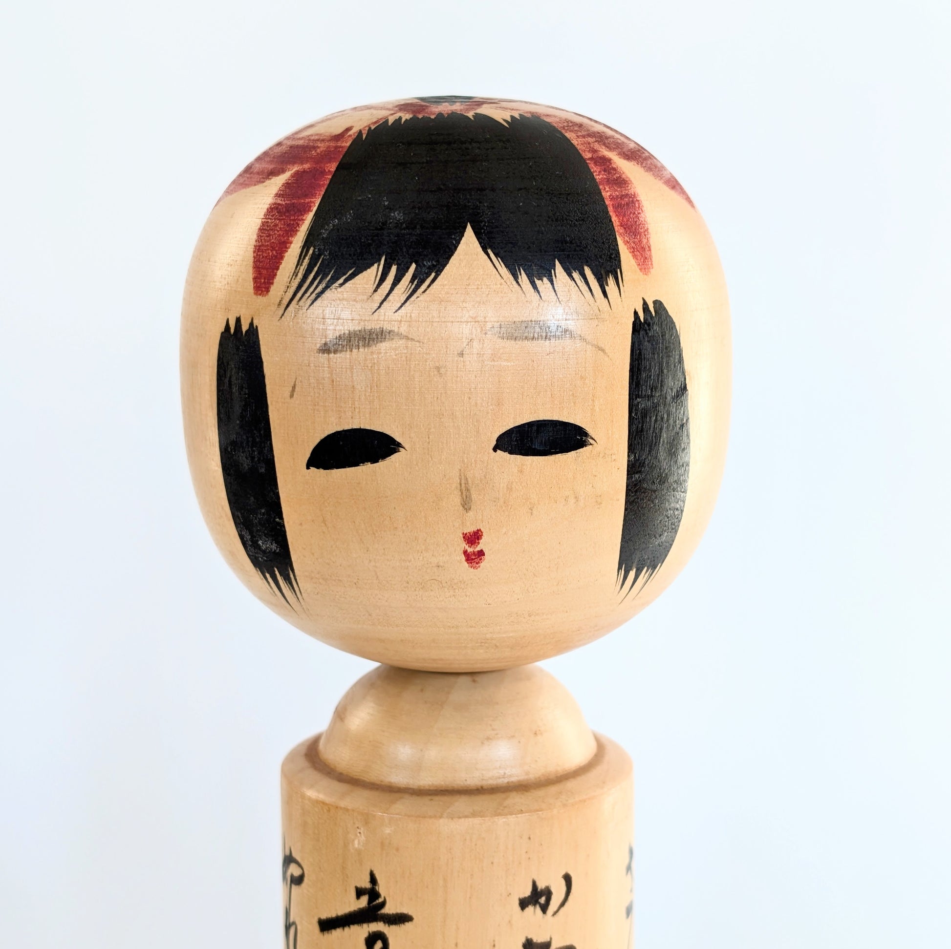 Visage peint à la main d’une kokeshi japonaise en bois signée Usuki Hakuhō