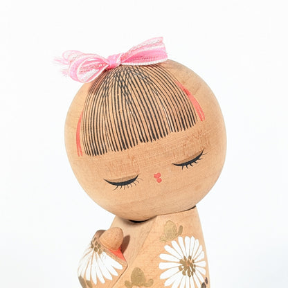 visage kokeshi japonaise cheveux peints frange fine noeud rose expression douce artisanat bois