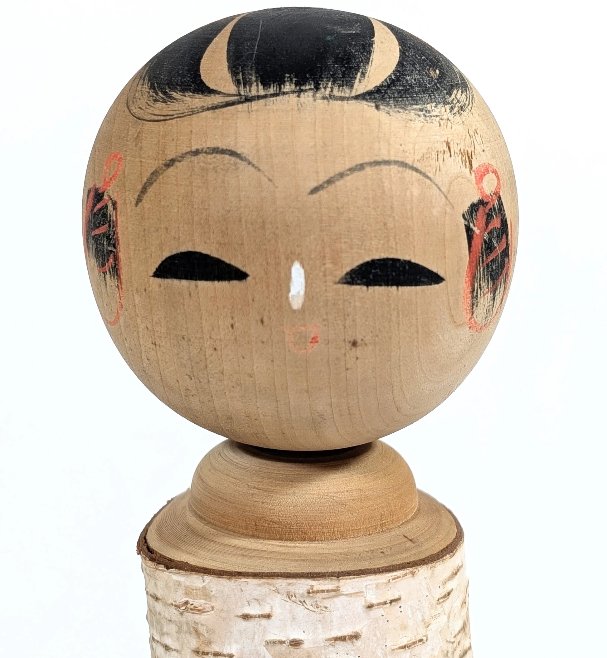 Visage peint à la main d’une kokeshi japonaise style Shōwa – artisanat japonais traditionnel.