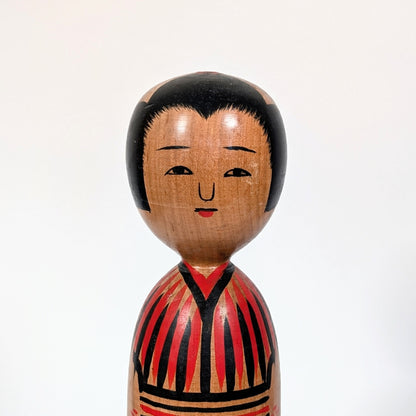 Visage peint d’une kokeshi japonaise traditionnelle, expression douce, artisanat japonais ancien