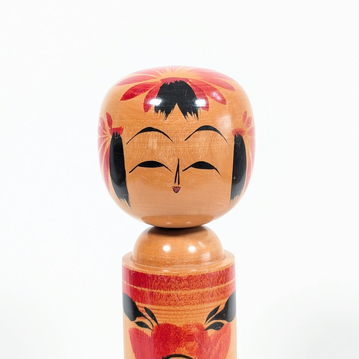 Visage souriant d’une kokeshi shingata Takeshi 武志 avec fleurs de camélia japonais tsubaki 椿