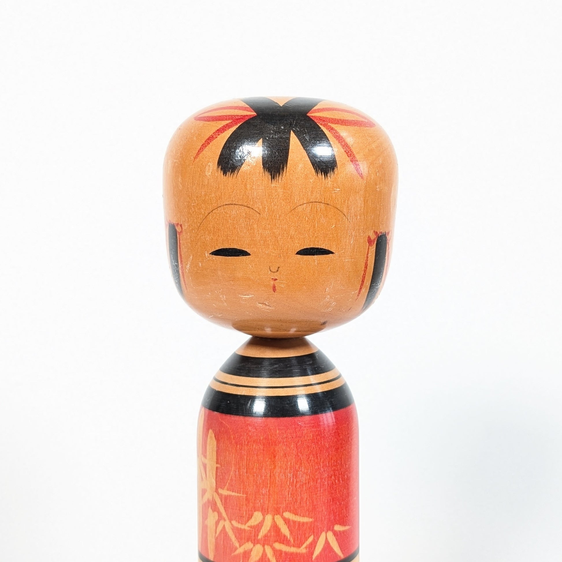 Détail du visage d’une kokeshi sosaku Kawamura Shōji avec coiffure noire et expression douce