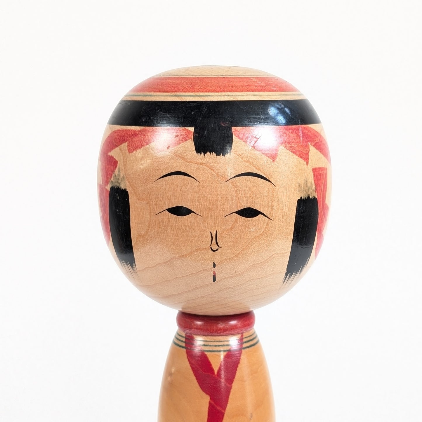 Gros plan du visage traditionnel d’une kokeshi Yajiro signée Ishikawa Tokujiro, réalisée au Japon vers 1972-1973