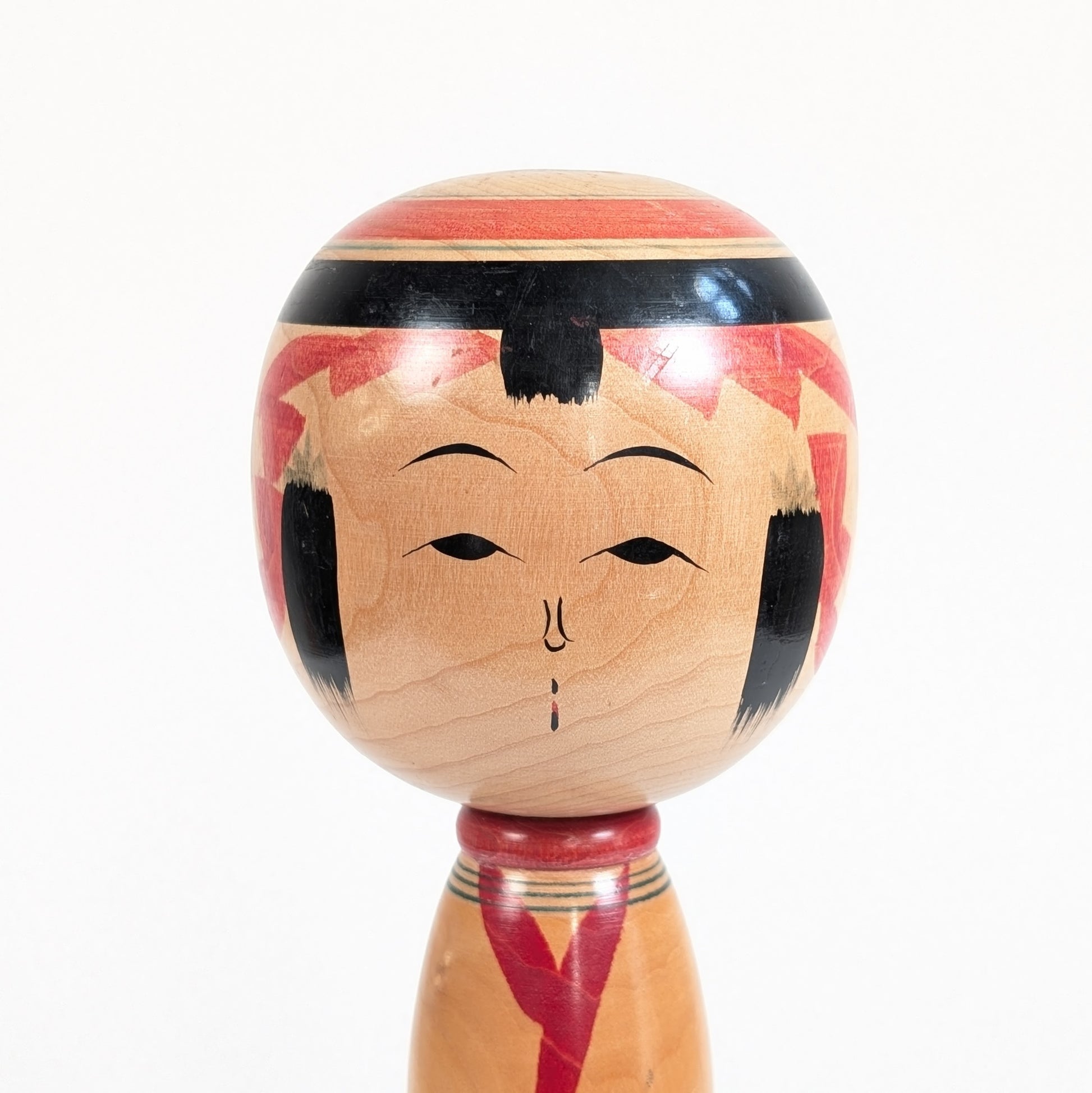 Gros plan du visage traditionnel d’une kokeshi Yajiro signée Ishikawa Tokujiro, réalisée au Japon vers 1972-1973