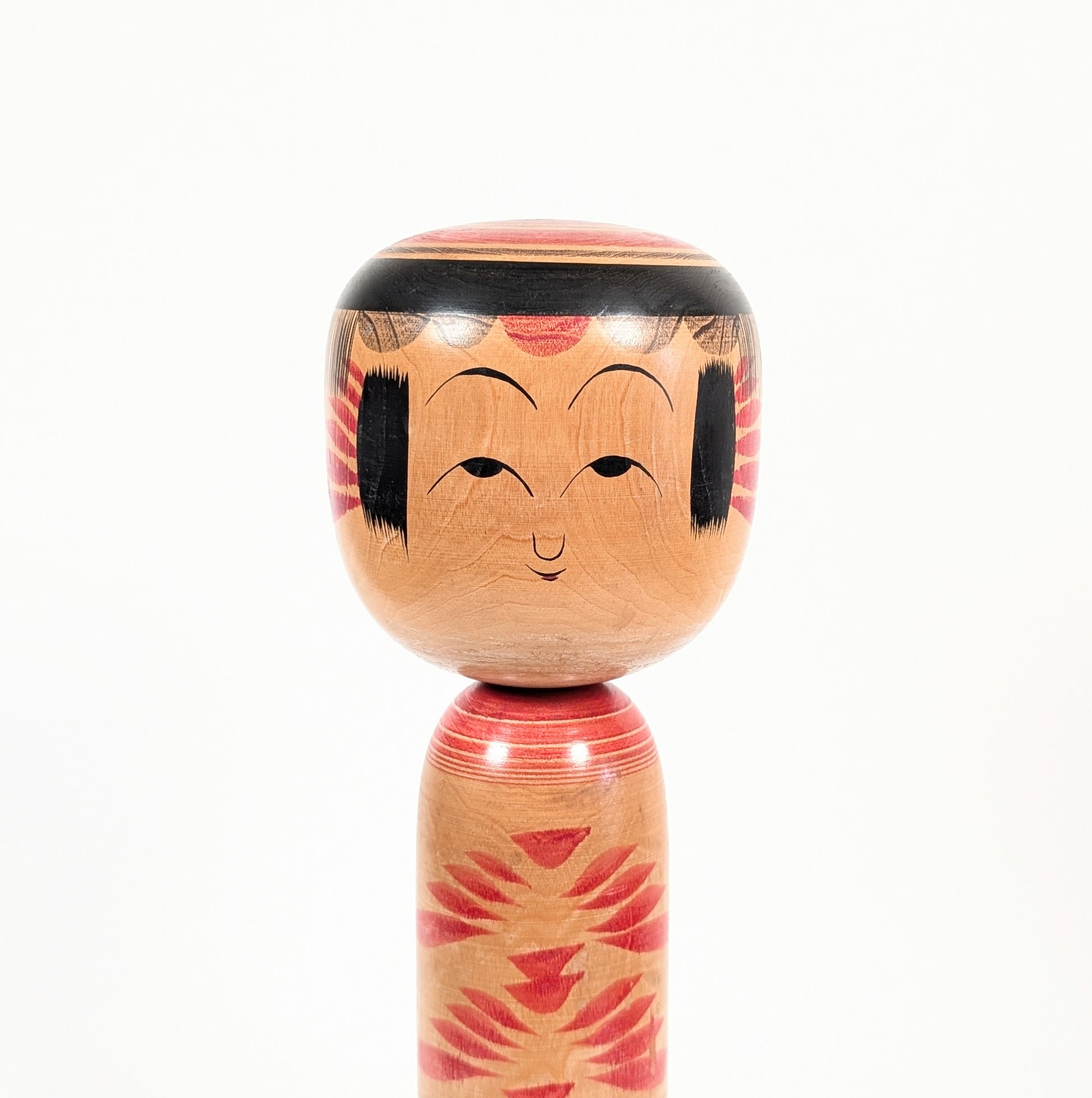 Gros plan sur le visage peint de la kokeshi Yajirō par Kamata Kōichi, avec frange noire et traits traditionnels délicats.