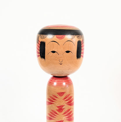 Gros plan sur le visage peint de la kokeshi Yajirō par Kamata Kōichi, avec frange noire et traits traditionnels délicats.