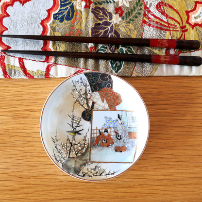 Assiette Kutani vue du dessus, accompagnée de baguettes et d’un tissu japonais coloré