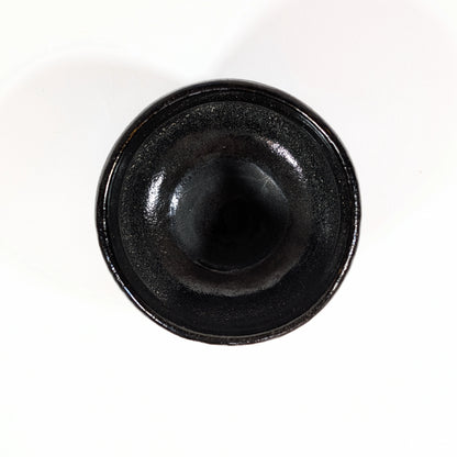 Vue du dessus d’un chawan en kuro raku fabriqué par Sasaki Shoraku, montrant l’intérieur sombre et brillant du bol.