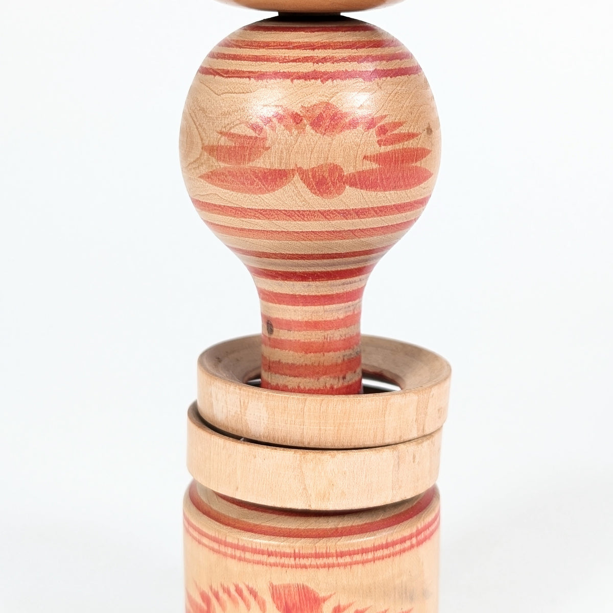 Détail d’une Yamiyo kokeshi à anneaux mobiles, décor rokuro-moyō et motif floral de chrysanthème kiku.