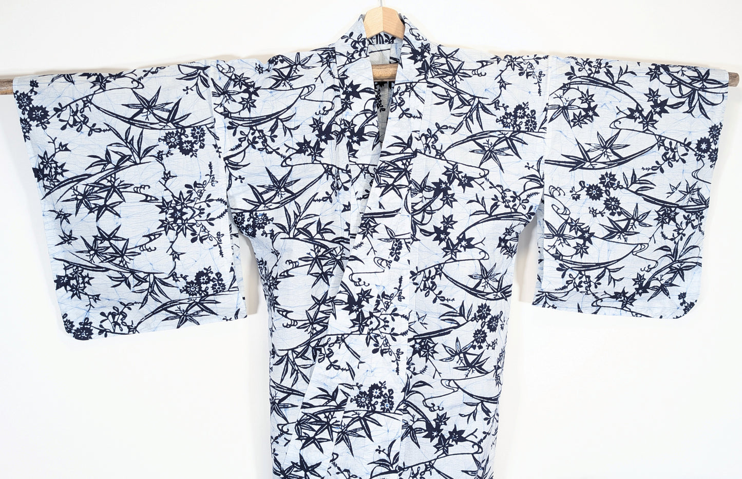 Yukata japonais authentique présenté manches déployées, fond blanc et décor bleu indigo de feuilles et fleurs