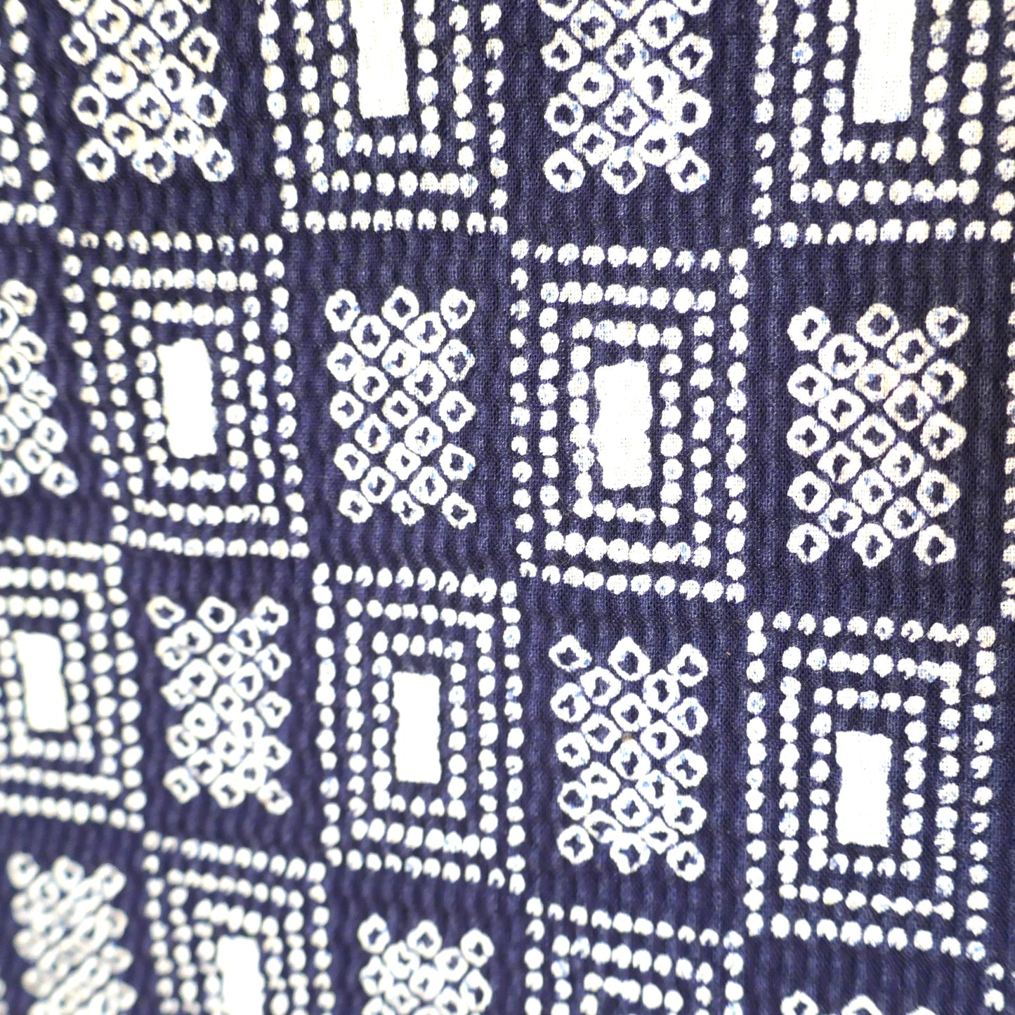 Zoom sur le motif géométrique du yukata, inspiré du style shibori sur fond bleu foncé.