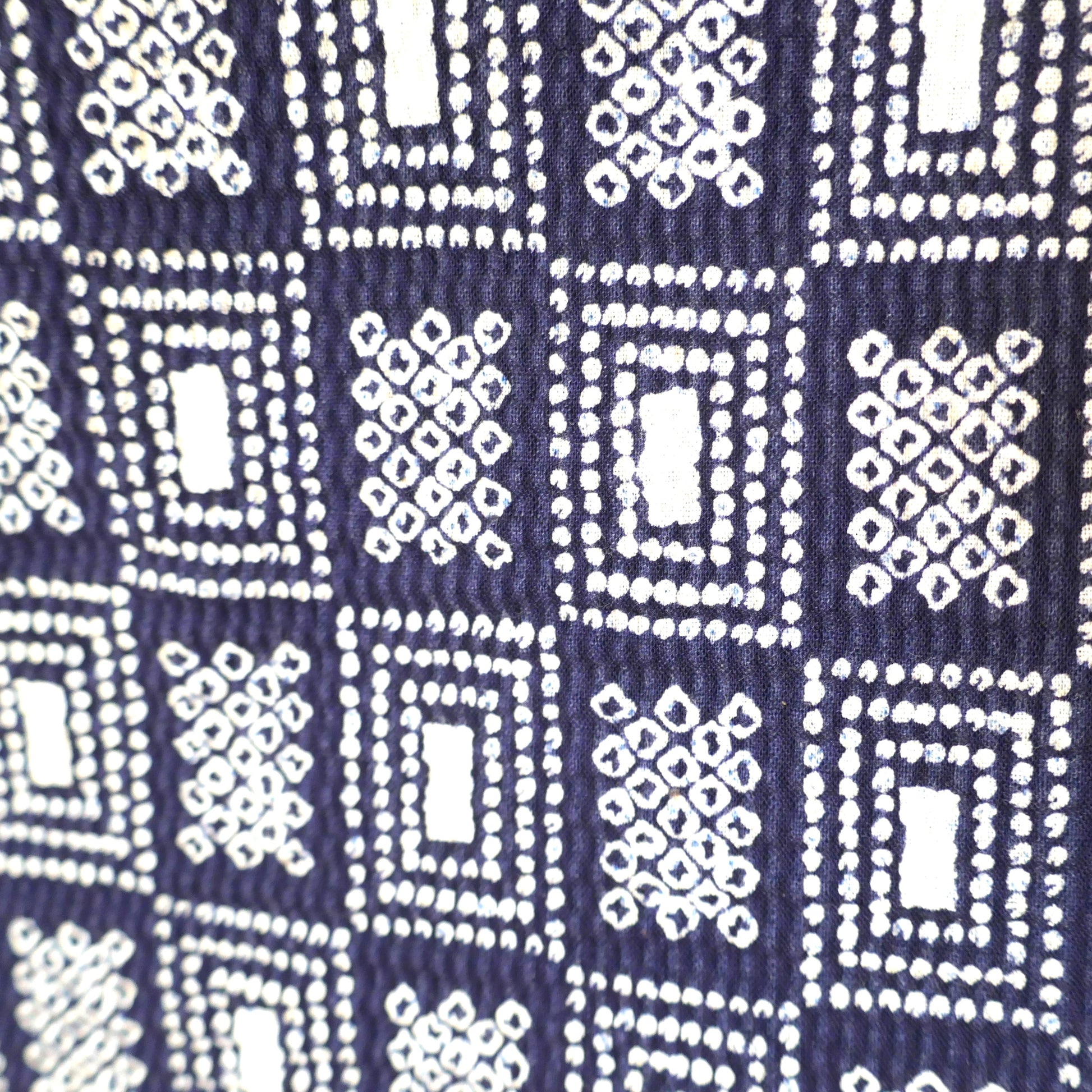 Zoom sur le motif géométrique du yukata, inspiré du style shibori sur fond bleu foncé.