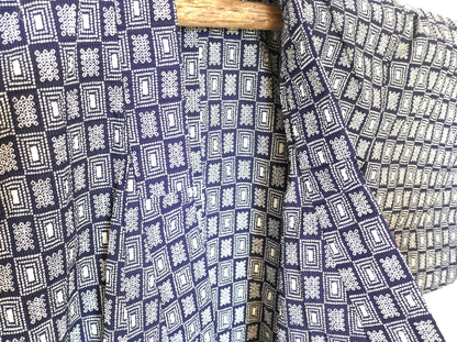 Gros plan sur le col du yukata, révélant les motifs géométriques blancs et la texture du coton crépé.